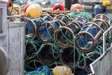 Fishing traps stacked on boat with ropes and buoys ready for use