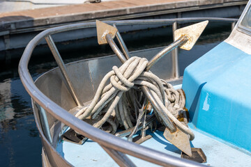 Grapnel with rope on the bow of a fishing boat moored in the port