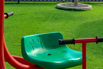 Green Plastic Seat on Playground with Red Frame and Green Turf