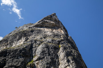 majestic, towering rock peak under a clear blue sky with sparse clouds, perfect for representing...