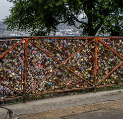 Image of hundreds of padlocks attached to a red metal fence in Paris.