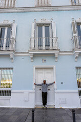 Doorway Embrace: A figure stands before an inviting building, arms outstretched to embrace the...