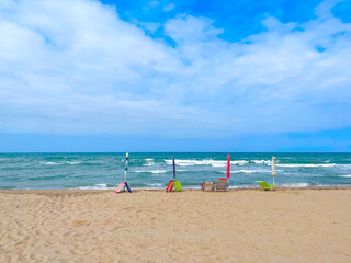 four closed beach umbrellas and beach chairs placed on the beachfront, to reserve a place in the...