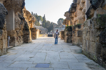Explorer of the Ancient Ruins of Italica: A lone explorer examines an ancient Roman structure,...