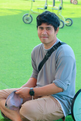 Smiling Man Wearing Gray Shirt Sitting on Green Lawn Outdoors