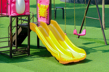 Colorful Outdoor Playground with Yellow Slide and Pink Swings on Green Lawn