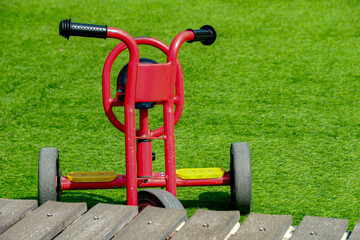 Bright Red Tricycle on Green Grass, Wooden Ramp Toy Vehicle on Playground