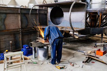 Male worker grinding machine part in metalworking factory