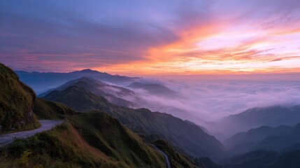 Obraz premium Scenic view of winding mountain road with fog-filled valley under a colorful sunrise sky.