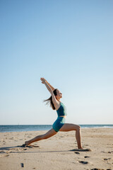 Young woman practicing warrior yoga poses on a sunny beach. Strength, balance, and mindfulness in nature during a peaceful outdoor workout
