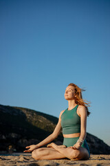 Woman practicing morning meditation in lotus pose on a sandy beach. Peaceful coastal setting,...