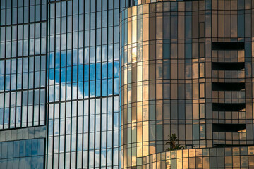 Abstract reflection of sky and clouds on modern glass building facade with colorful windows