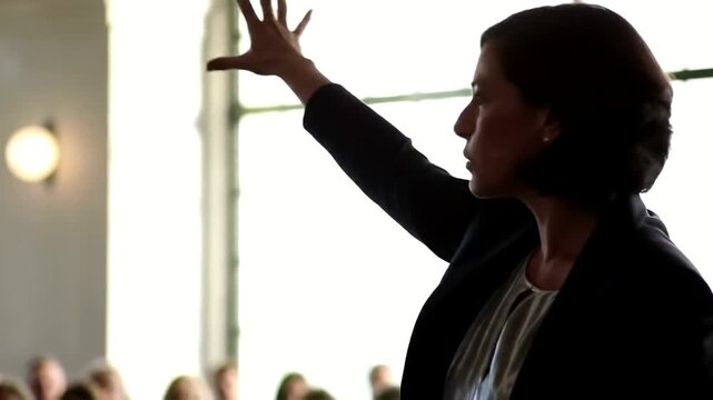Businesswoman giving a presentation to an audience in a bright room.