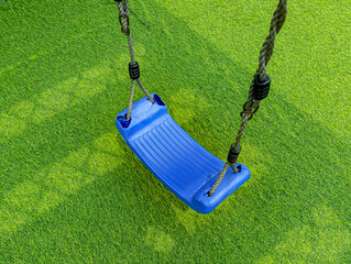Blue Plastic Swing with Ropes Hanging Over Green Turf