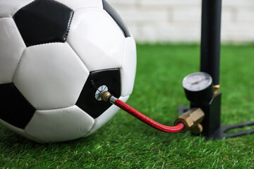 Soccer ball and manual air pump indoors, closeup