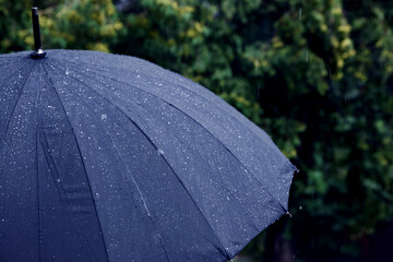 Blue umbrella under heavy rain outdoors, closeup. Space for text