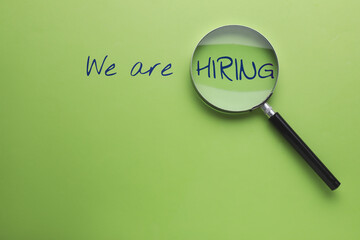 We are hiring. Inscription and magnifying glass on green background, top view