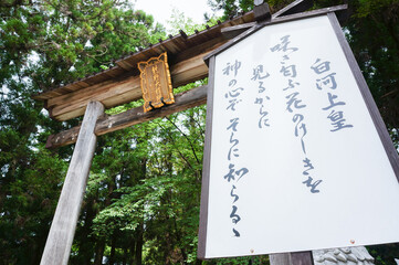神社の大きな鳥居と手書き看板に囲まれた参道入口