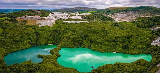 Aerial view of clay mining site in Cornwall with machinery, winding roads, and rural landscape...