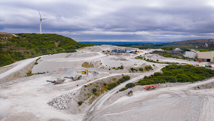 Aerial view of clay mining site in Cornwall with machinery, winding roads, and rural landscape...