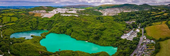 Aerial view of clay mining site in Cornwall with machinery, winding roads, and rural landscape...