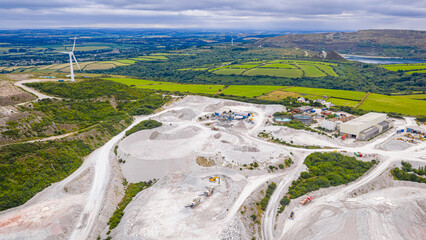Aerial view of clay mining site in Cornwall with machinery, winding roads, and rural landscape...