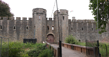 Cardiff Castle main entrance with wooden bridge leading to gatehouse and Welsh flag waving