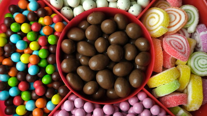 A vibrant candy tray filled with chocolate-covered treats, jelly candies, sugar-coated sweets, and...