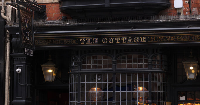 CARDIFF, UK - AUGUST 8, 2025 - Traditional english pub The Cottage in Cardiff, Wales, displaying its peculiar black facade and golden sign
