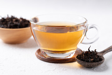 Black tea in cup glass with dried tea leaves on white background, Healthy herbal hot drink