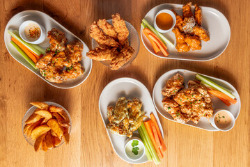 Fried Buffalo wings with medium-spiced sauce, served on a wooden board with homemade ranch dip