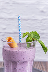 Tall glass of blueberry and Greek yogurt smoothie, topped with crunchy granola and a sprinkle of...