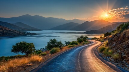 Obraz premium Winding road leads to sunset over lake and mountains