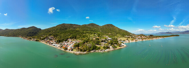 Aerial view of a pristine tropical beach in Florianópolis, Brazil, with lush green forest,...
