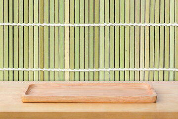 Empty sushi board on wood table with bamboo background. Top view of plank wood for graphic stand product, interior design or montage display your product.