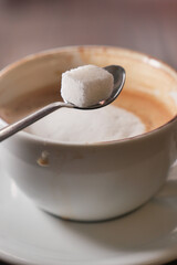 Coffee with sugar cube on a spoon ready to stir