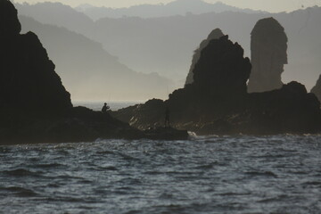 Rocky Coastline with Ocean Waves and Mountain Silhouette