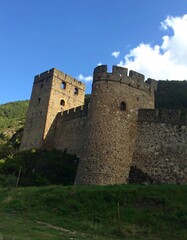 Ancient stone fortress ruins on hillside, partially overgrown with vegetation
