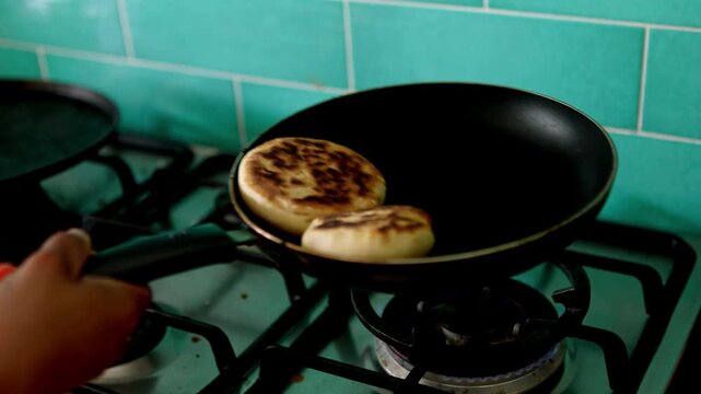 Chef flipping arepas in a pan