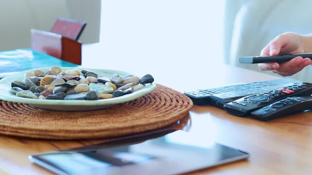 Person Picking Up Remote Control from Coffee Table