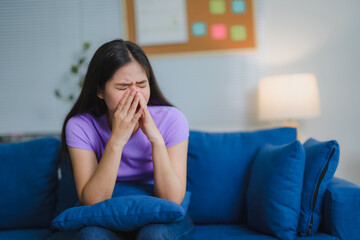 Young Asian Woman Crying While Sitting on Sofa in Living Room