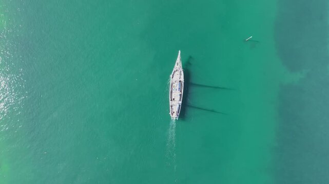 Overhead drone clip of a wooden ship salling through clear green seawater