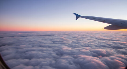 Obraz premium View from an airplane window of clouds at sunset with wing tip