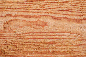 Close up showing the texture of a solid piece of reddish wood with prominent grain patterns, knots...