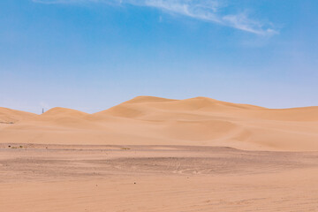 Desert Dunes And Puffy White Clouds Under Bright Blue Sky
