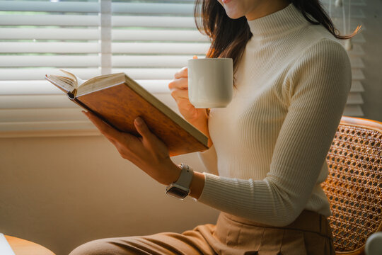 Woman enjoying a book and coffee near window
