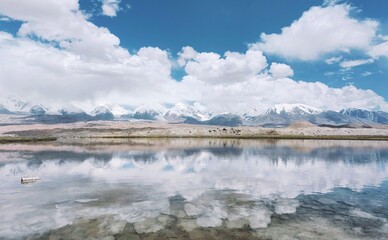 Pristine Mirror Lake Reflecting Blue Sky And Snow Capped Mountains With White Clouds In Majestic...