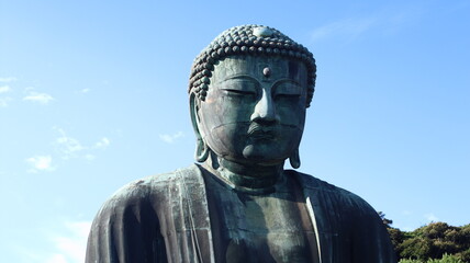 The great bronze statue of Buddha rises, serene and unchanging, before the hundreds who visit each...