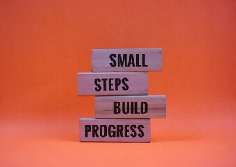 Wooden Blocks Displaying Motivational Words 'small, steps, build, progress'.with Orange Background