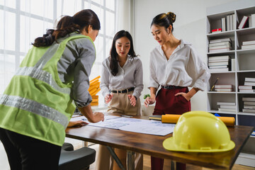 Construction engineer explaining building plan to businesswomen